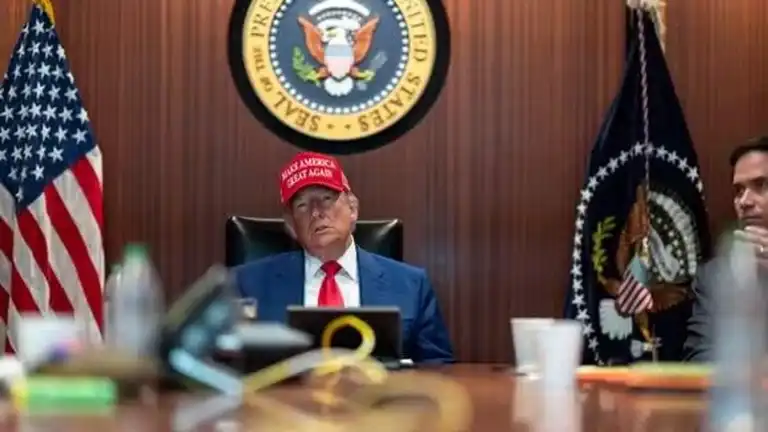 Donald Trump assis dans une salle officielle, portant une casquette Make America Great Again