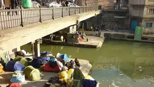 Campement précaire d’immigrés sous un pont en zone urbaine