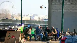 Groupe d’hommes sans-abris discutant sous un pont à Paris