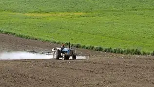Agriculteur pulvérisant des produits sur un champ, symbole des enjeux de la loi Duplomb.