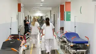 Couloir d’hôpital français avec lits vides et personnel soignant en activité.