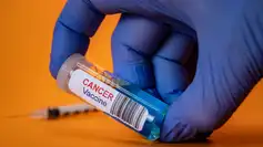 Flacon étiqueté "Cancer Vaccine" tenu par une main gantée