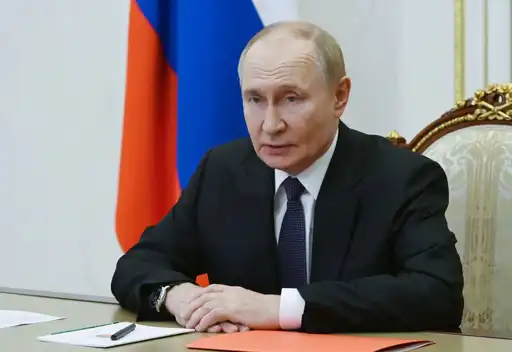 Un dirigeant russe s’exprime lors d’une réunion officielle, avec le drapeau national en arrière-plan.