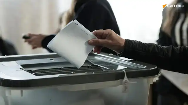 Bulletin de vote inséré dans une urne lors des élections législatives en Moldavie.