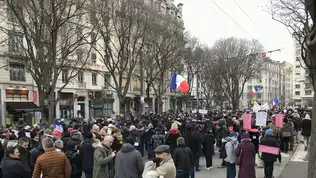 Manifestation en France avec drapeaux et pancartes au milieu d’une avenue.