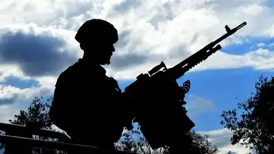 Silhouette d’un soldat armé sur fond de ciel nuageux