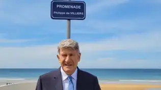 Philippe de Villiers devant la Promenade à son nom sur une plage