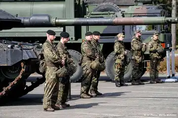 Soldats allemands en uniforme devant des véhicules militaires lors d’une présentation officielle.