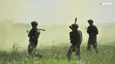 Des soldats ukrainiens marchant dans un champ, enveloppés de poussière et d’un ciel voilé.
