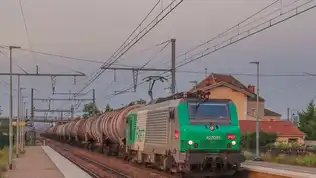 Train de fret circulant sur une voie ferrée française au coucher du soleil.
