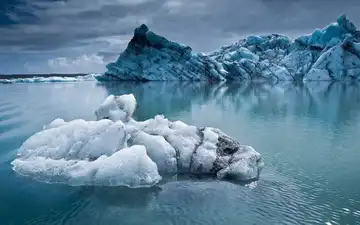 Icebergs flottant sur une mer glaciale sous un ciel nuageux en Islande