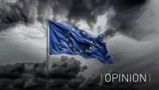 Image d'un drapeau de l'Union européenne flottant dans un ciel nuageux, symbolisant l'incertitude et les défis politiques.
