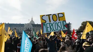 Image de manifestants brandissant des pancartes avec les mots "STOP MERCOSUR", symbolisant l'opposition à l'accord UE-Mercosur.