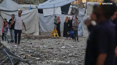 Scène de civils à Gaza dans un camp détruit, observant les débris après des bombardements.