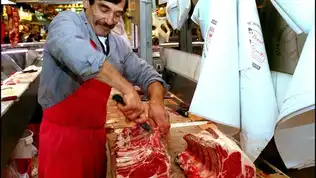 Boucherie traditionnelle avec un boucher travaillant sur de la viande.
