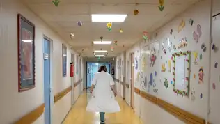 Couloir d'un hôpital français avec des décorations murales, illustrant l'environnement hospitalier.