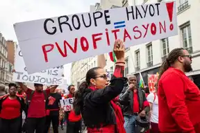 Manifestation contre le Groupe Hayot, avec des citoyens brandissant des pancartes.