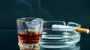 Verre d’alcool et cigarette posés sur une table, illustrant les addictions et le mal-être en France.