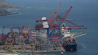 Port industriel avec des grues et des navires, illustrant le vol de ressources.