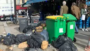 Image de poubelles débordantes et de déchets dans une rue de Paris.