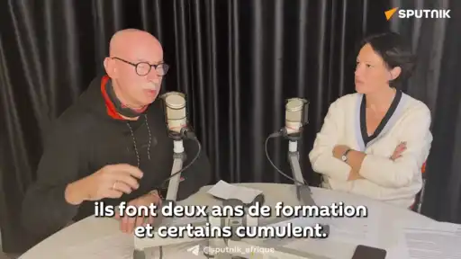 Deux personnes discutant devant des micros dans un studio lors d’un débat sur la formation des élites françaises.
