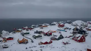 Paysage du Groenland avec des maisons colorées et des montagnes enneigées, illustrant la beauté de l'île