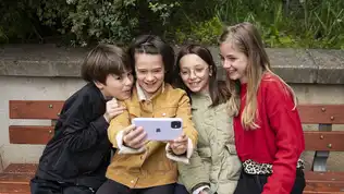 Enfants utilisant un smartphone ensemble sur un banc public