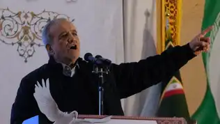 Homme en costume noir parlant devant un micro, illustrant un discours sur les revendications socio-économiques