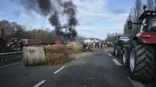 Blocage routier d’agriculteurs avec tracteurs et bottes de paille en feu.