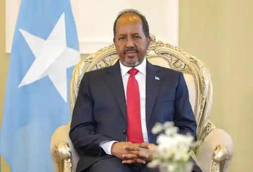 Portrait officiel du président somalien Hassan Sheikh Mohamud assis devant le drapeau national.