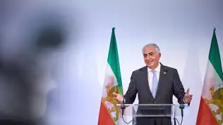 Reza Pahlavi lors d’une prise de parole avec drapeau iranien en arrière-plan