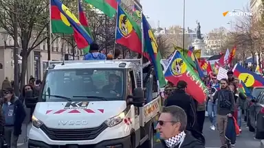Manifestants avec drapeaux de la Kanaky et syndicat USTKE derrière un camion de chantier blanc.