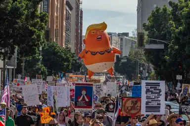 Manifestation de rue avec un grand ballon gonflable parodiant Donald Trump en bébé.