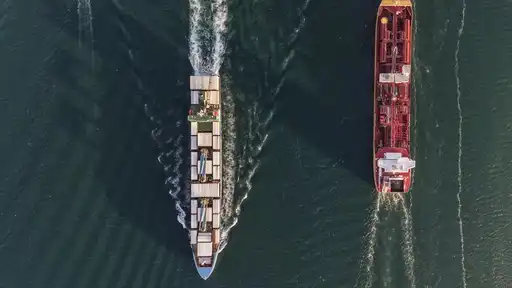Vue aérienne verticale de deux navires de transport naviguant sur une mer sombre.
