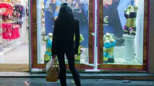 Silhouette d'une jeune femme de dos devant une vitrine de magasin de lingerie de nuit.