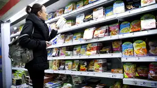 Une cliente examine des produits alimentaires dans le rayon frais d'un supermarché.
