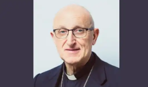 Portrait de Monseigneur Dominique Rey en habit ecclésiastique sur fond gris clair.