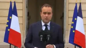 Sébastien Lecornu s'exprimant devant des drapeaux français et européens à Paris.