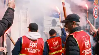 Manifestation de salariés Stellantis avec gilets CGT et fumigènes devant l'usine de Poissy.