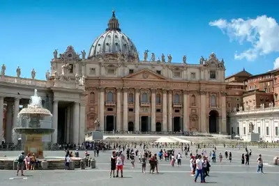 Vue d'ensemble de la place et de la basilique Saint-Pierre au Vatican sous un ciel bleu.