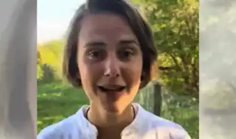 Portrait de profil d'une jeune femme souriante en chemise blanche dans un cadre naturel.