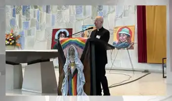 Prêtre au pupitre orné d'un drapeau arc-en-ciel et d'une icône religieuse.
