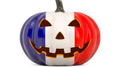 Citrouille d'Halloween peinte aux couleurs du drapeau français (bleu, blanc, rouge) avec un visage découpé.