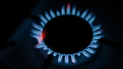 Gros plan sur les flammes bleues d'un brûleur de cuisinière à gaz allumé dans la pénombre.