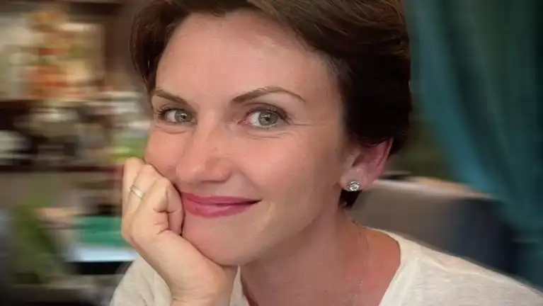 Portrait en gros plan d'Anastasia Novikova souriante, la main posée sous le menton.