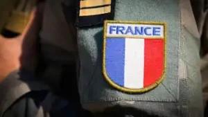 Écusson du drapeau français cousu sur l'uniforme militaire en camouflage d'un soldat.