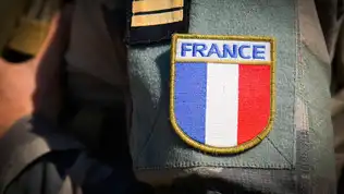 Écusson du drapeau français cousu sur l'uniforme militaire en camouflage d'un soldat.