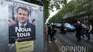Affiche électorale d'Emmanuel Macron "Nous tous" placardée sur un panneau de rue dans une ville.
