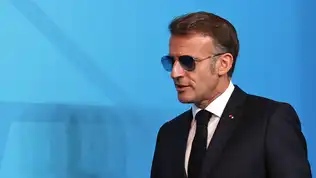 Portrait en gros plan d'Emmanuel Macron portant des lunettes de soleil d'aviateur sur fond bleu