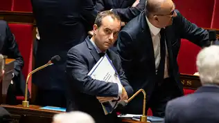 Sébastien Lecornu tenant un dossier sous le bras dans l'hémicycle de l'Assemblée nationale.
